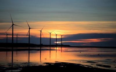 Wind turbines next to water during a sunset